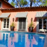 Striped awning over doors and Windows in a backyard with a pool